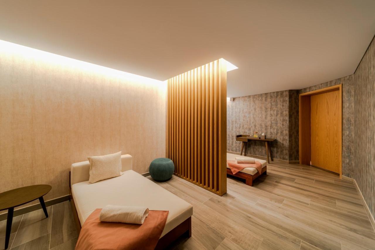 Five Jumeirah Village Dubai Exterior photo The photo depicts a calm and modern interior space, likely a relaxation or wellness area. It features a light-colored wood floor and soothing wall textures. 

On one side, there’s a daybed with soft cushions, accompanied by a small round table. A blu